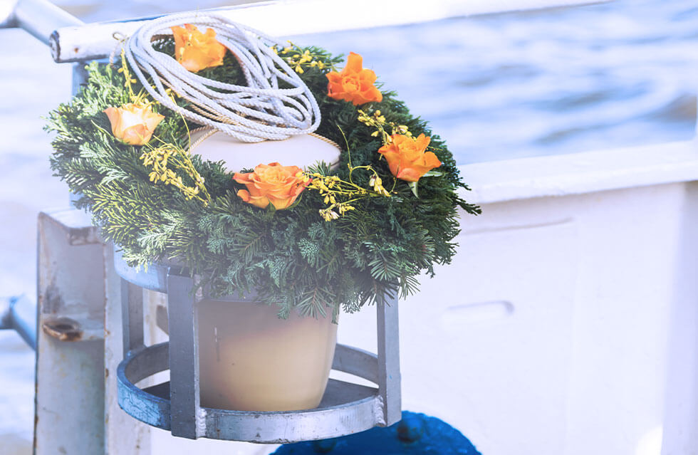 Urne mit Tannen/Rosenkranz auf einem Schiff